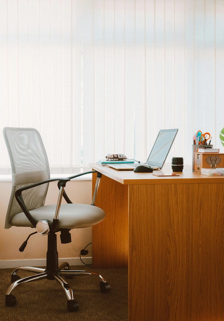 Modern office with a wooden desk, chair, laptop, and organized accessories.